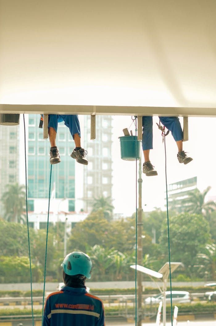 Professional window cleaners maintain a skyscrapers facade with safety gear. Urban scene.