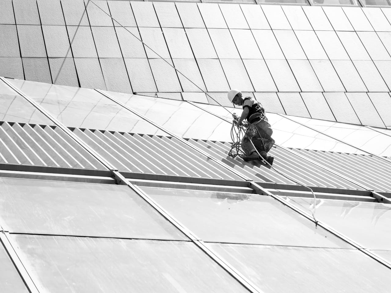 A maintenance worker in safety gear performs tasks on a skyscrapers glass facade.